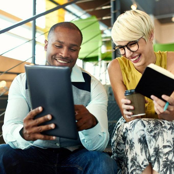 Team of young casual business people collaborating on an online project using a digital touchpad tablet computer in a bright modern office space. Serie with light flares